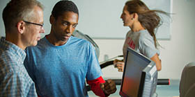 Student and professor monitor performance of an athlete on a treadmill